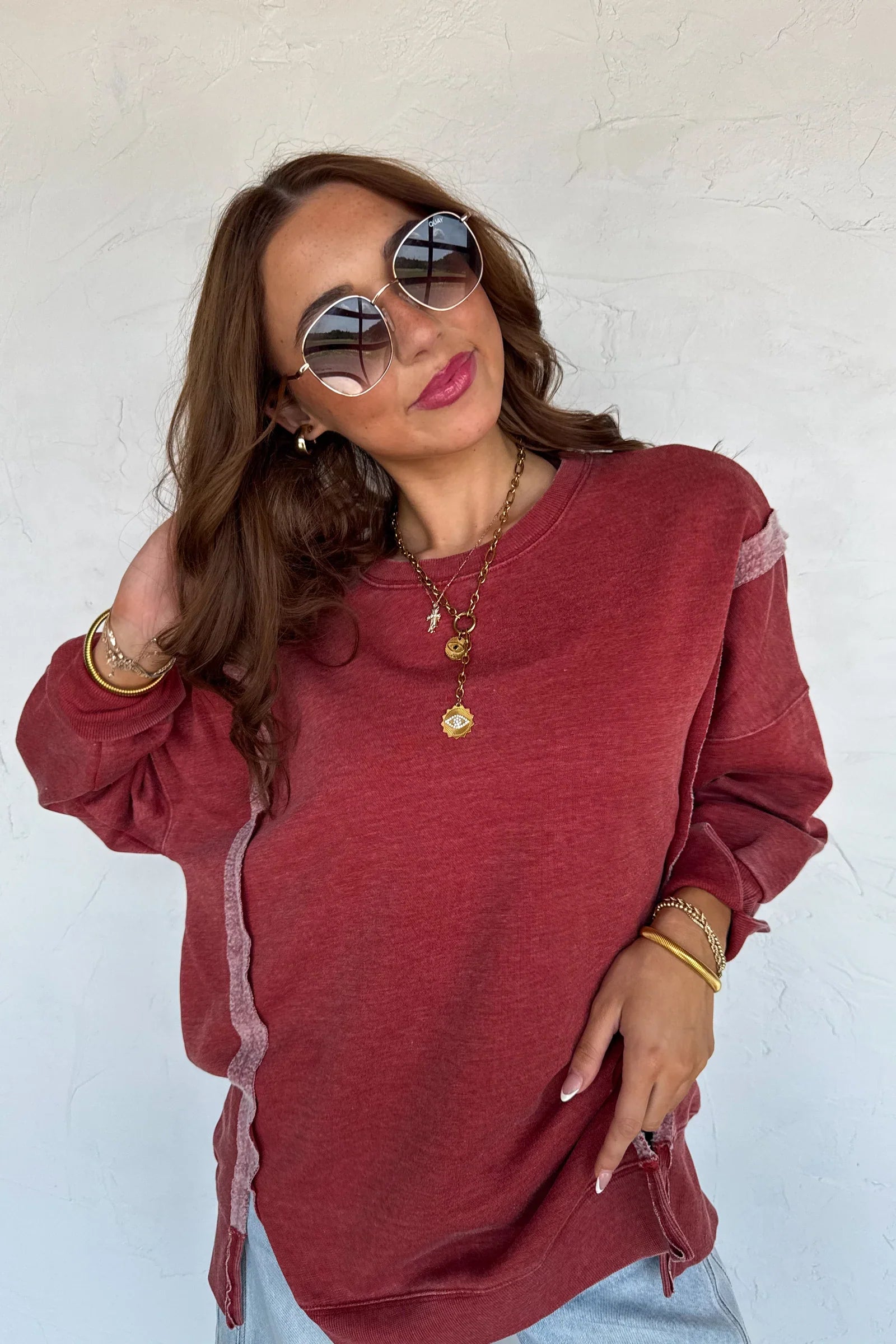 Woman wearing a vintage washed burgundy sweatshirt with raw edges against a white background