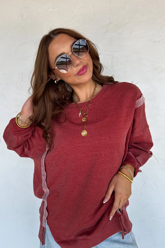 Woman wearing a vintage washed burgundy sweatshirt with raw edges against a white background