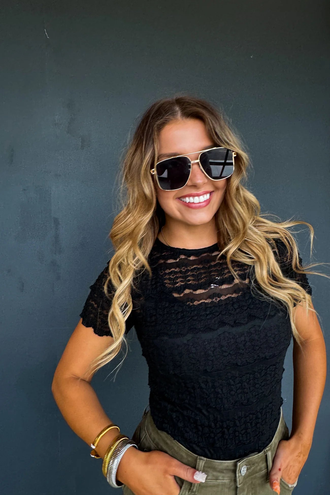 Woman wearing sunglasses and a black top against a dark background