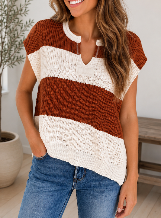 A woman wearing a chunky knit short-sleeve henley top with wide horizontal stripes in rust brown and cream, paired with blue jeans in a bright indoor setting.